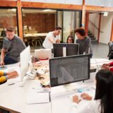 Casually Dressed Business Team Working At Desks In Modern Open Plan Office
