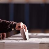 Hand of a person casting a vote into the ballot box during elections
