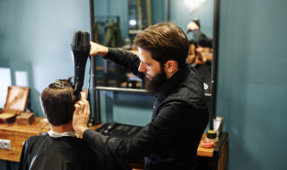 The Barber man in the process of drying a clients hair with a Hairdryer at the hairdresser