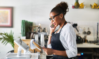 friendly waitress taking order on phone at restaurant and writing on notepad