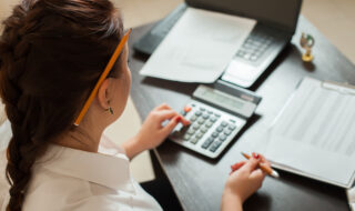 Young female bookkeeper uses calculator