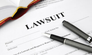 Close-up of a lawsuit document titled LAW SUIT with a pen resting across the page.