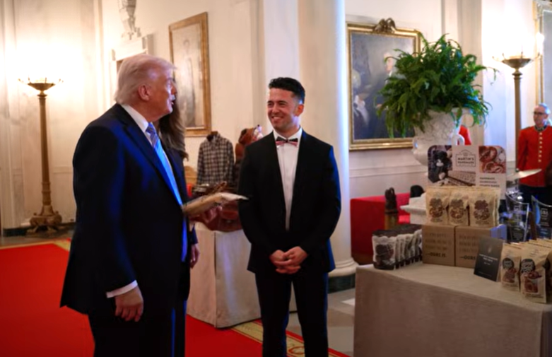 New York Member Spotlight Martins Pretzels White House May 2026 crop - NFIB An older man in a dark suit and blue tie shakes hands with a younger man in a black tuxedo on a red carpet in a formal hall with artwork and lamps in the background.