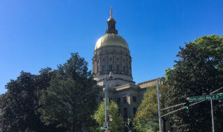 Golden-domed government building under a clear blue sky, framed by trees with a Martin Luther King Jr Dr street sign nearby.
