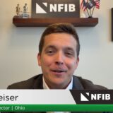 Video still of Jared Weiser, NFIB State Director for Ohio, speaking at a desk with framed diplomas on the wall and NFIB signage, plus a green lower-third displaying his name and title.